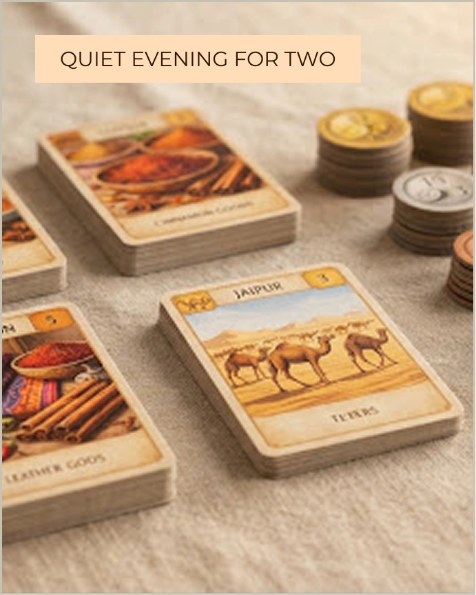 Close-up view of Jaipur board game cards featuring camels and goods with scoring tokens in the background