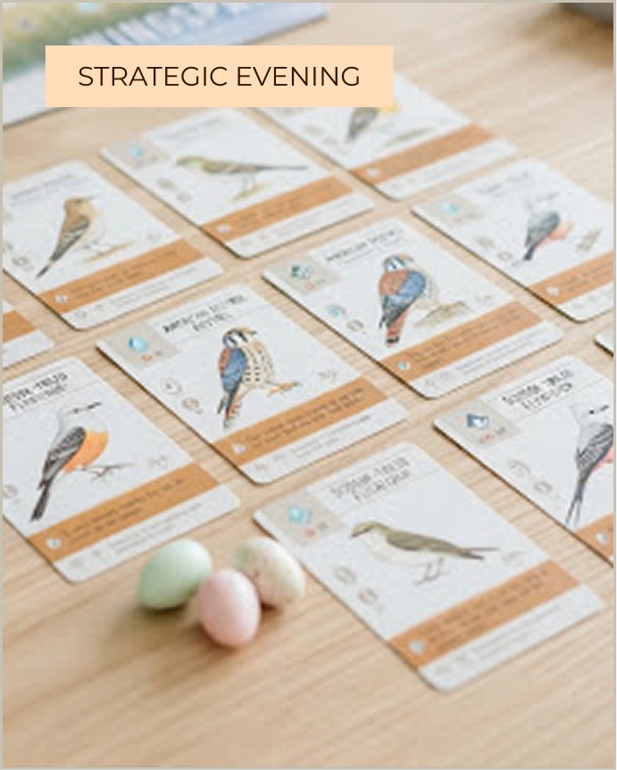 Illustrated bird cards and small pastel egg miniatures laid out on a wooden table from the Wingspan board game